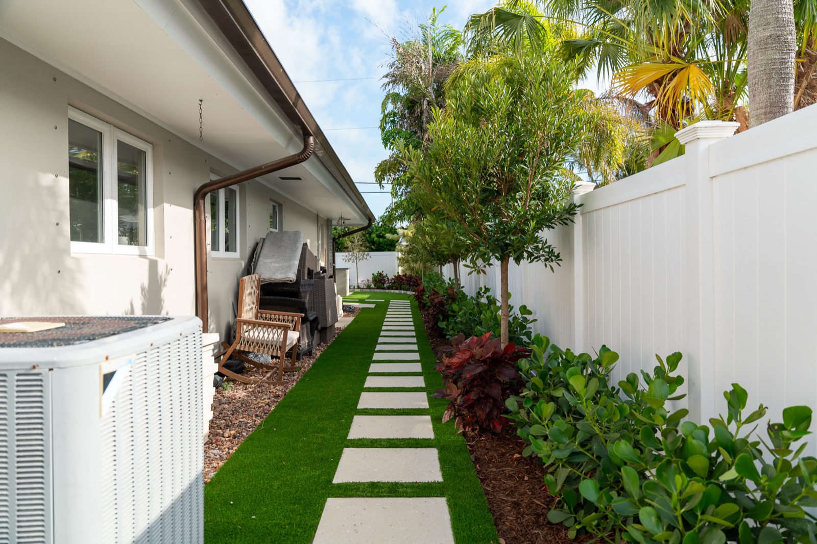 Paver stepping stones set in synthetic turf along a side yard