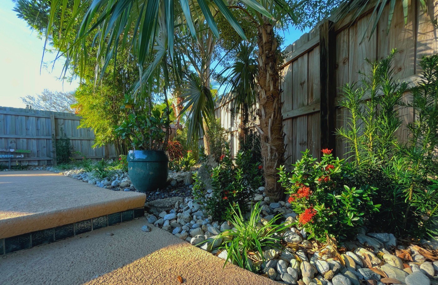 River rock beds with tropical plantings along a patio walkway
