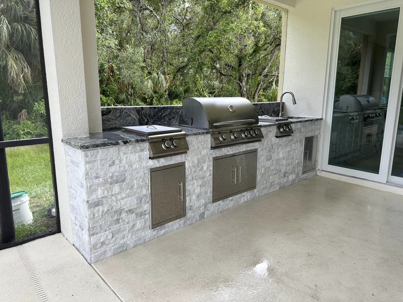 Stacked-stone outdoor kitchen with granite counters, built-in grill, side burners, and sink
