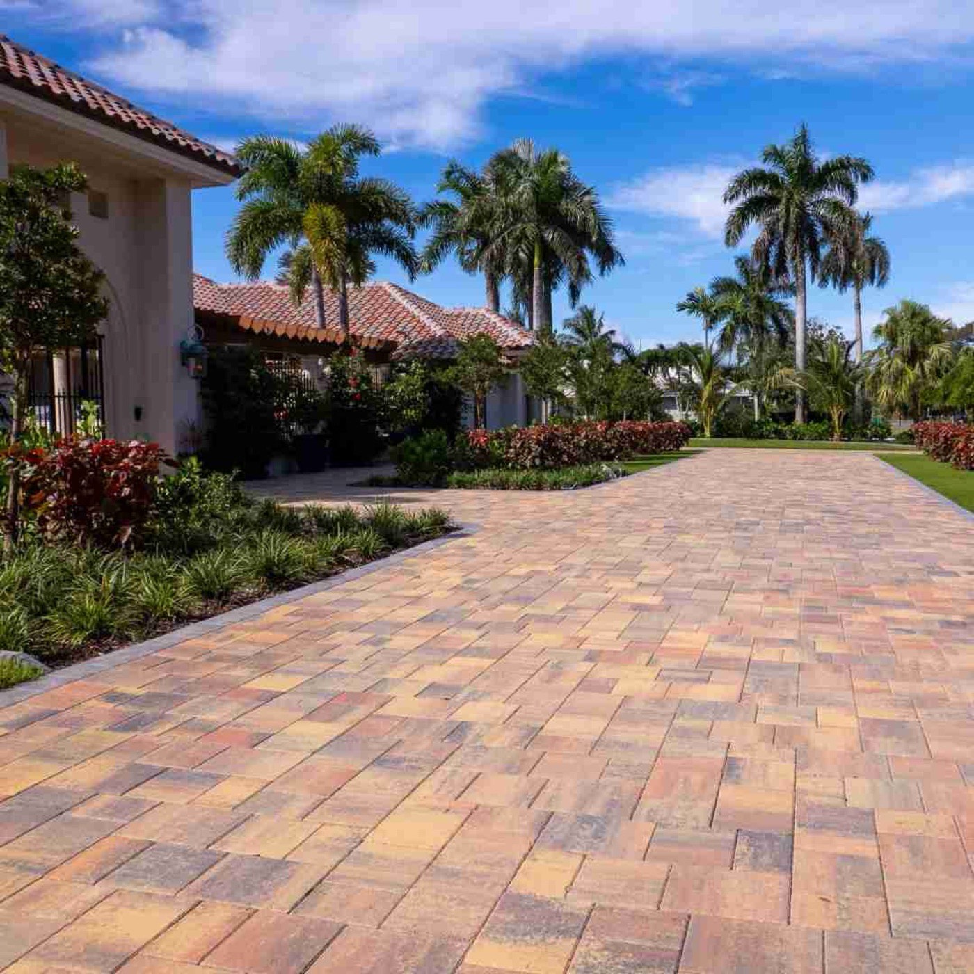 Wide interlocking paver driveway leading to a Mediterranean home