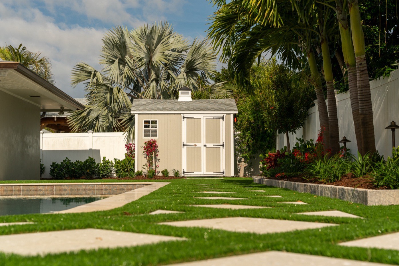 Synthetic turf backyard with paver stepping stones, pool, and garden shed