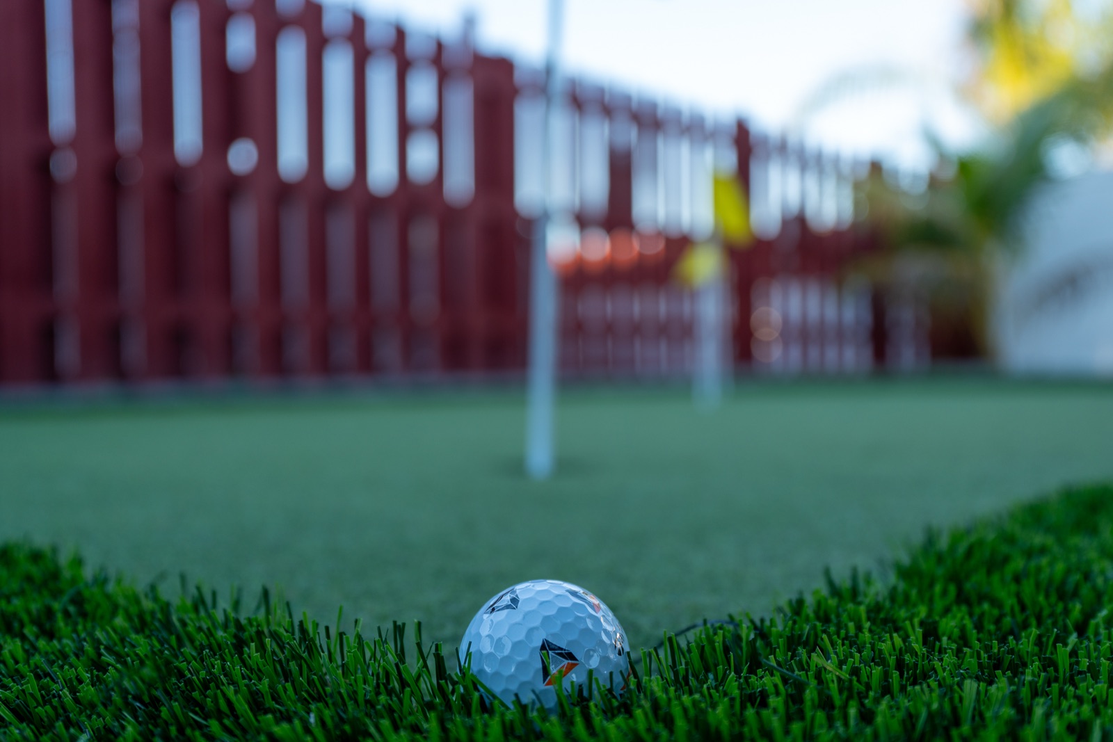 Golf ball resting on synthetic turf fringe beside a putting green