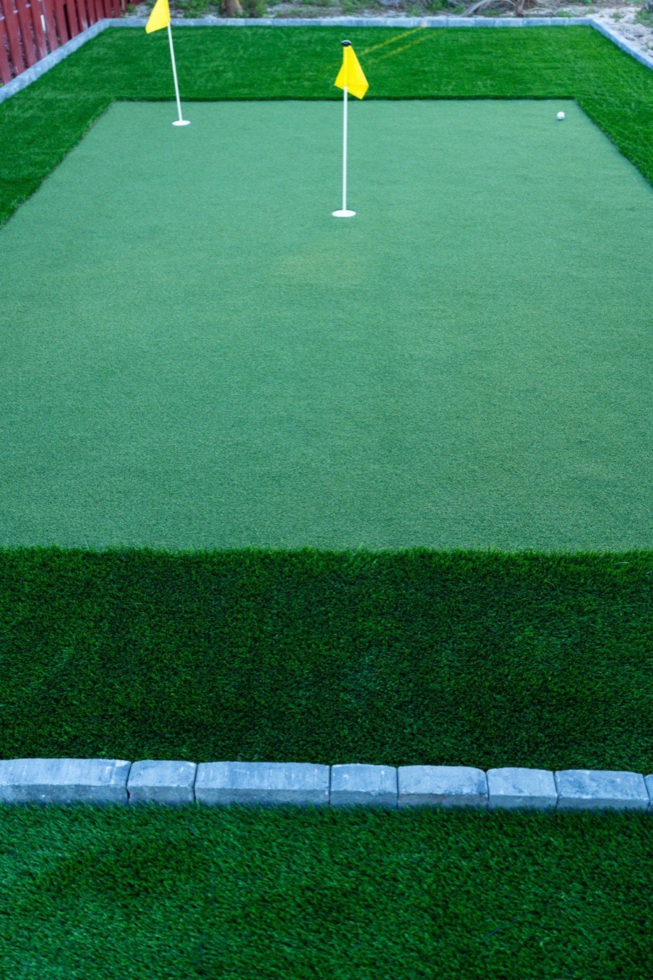 Backyard putting green with fringe turf and two flag holes